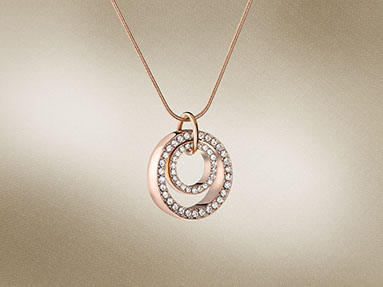 Ciondolo dorato con i cristalli composto da  due cerchi concentrici. Lo sfondo beige con il delicato texture della tela. Orizzontale.