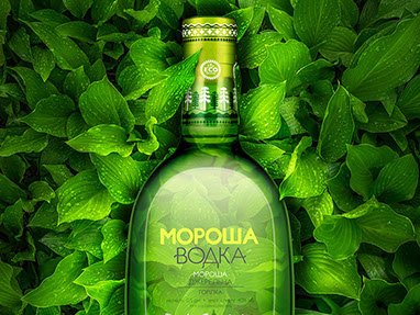 Una bottiglia di vodka sullo sfondo di foglie verdi. Leggera luce calda illumina le foglie intorno dall'interno della bottiglia.